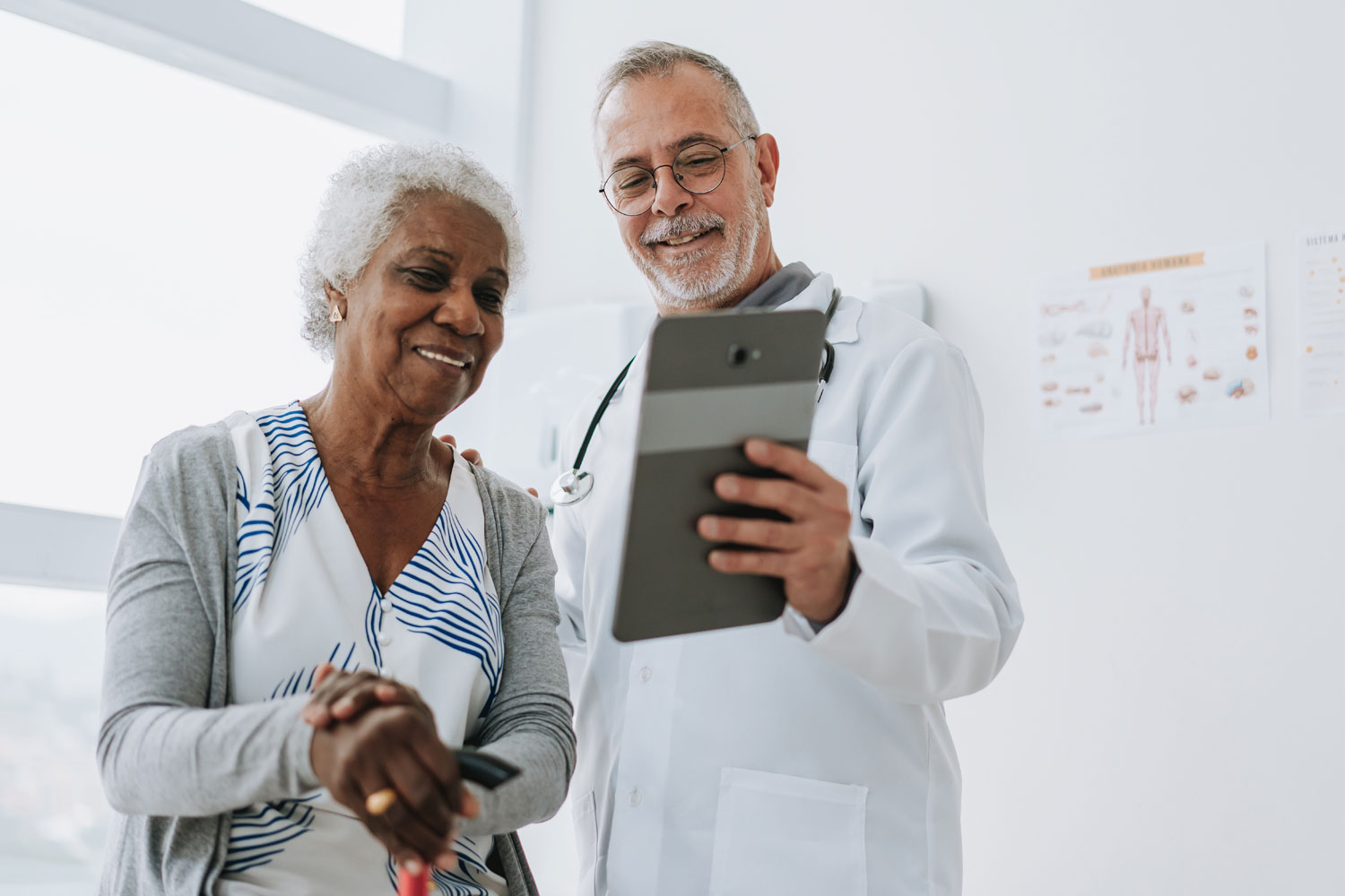 alt: a male doctor showing his female elderly patient results using a tablet 