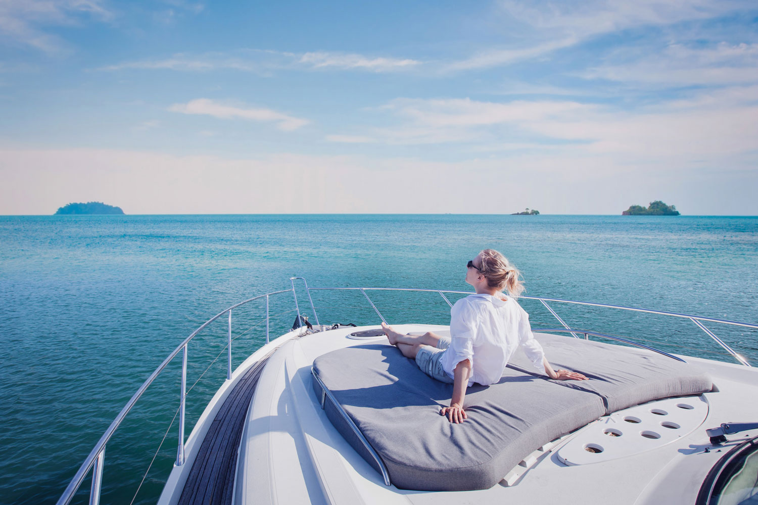 ALT Text: A woman on a boat looking out towards the aqua blue ocean