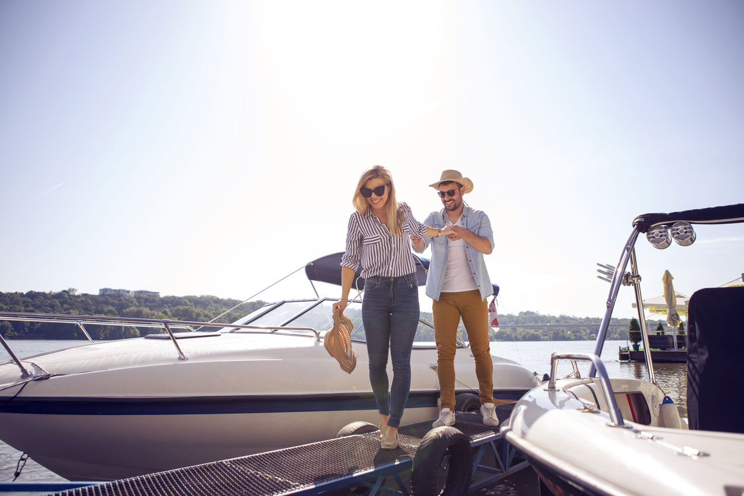 Alt Text: A man helping  woman getting off of a boat that's has been docked with the sun shinning in the back 